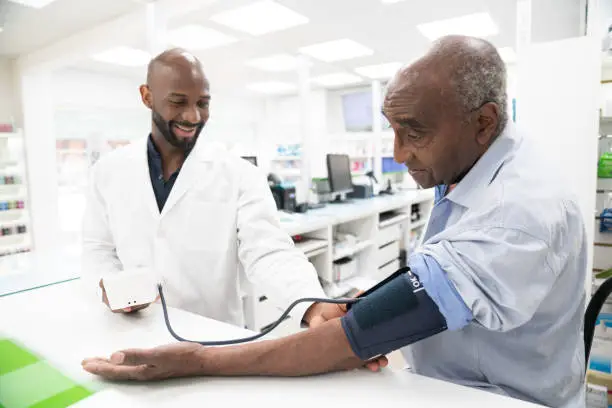 A clinician measuring a patient's blood pressure in a modern pharmacy