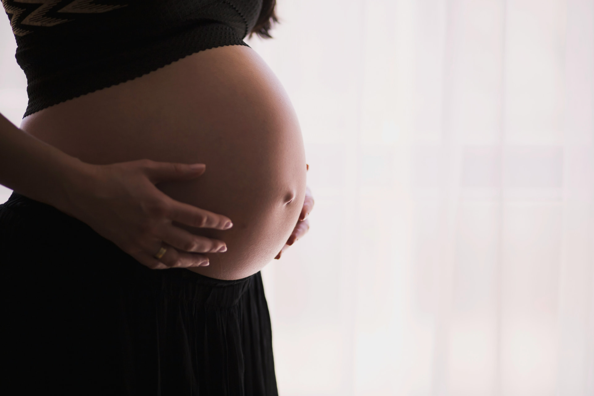 A pregnant woman gently holding her belly